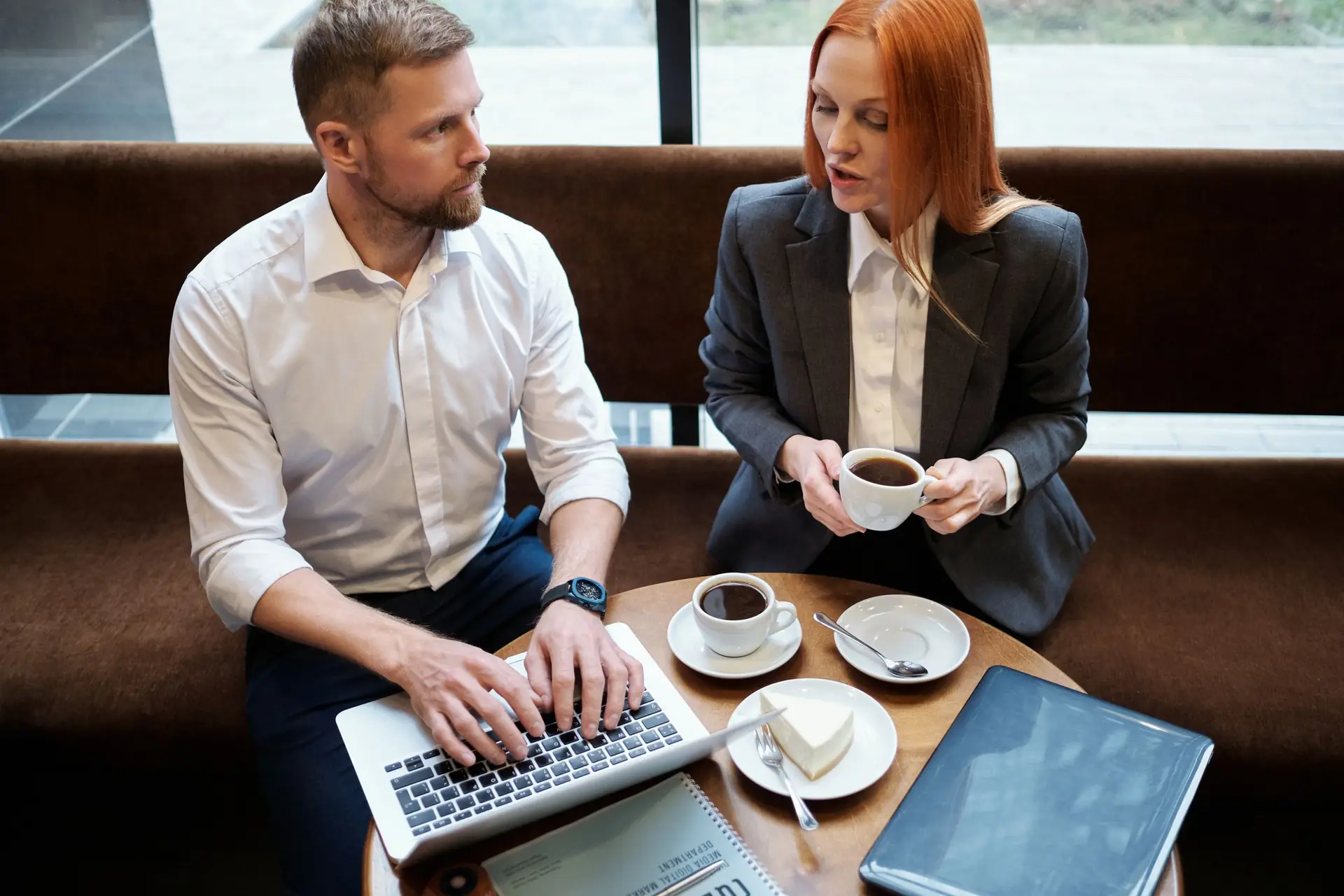 Zwei Gründungspersonen besprechen bei einem Kaffee ihre nächsten Schritte am Laptop