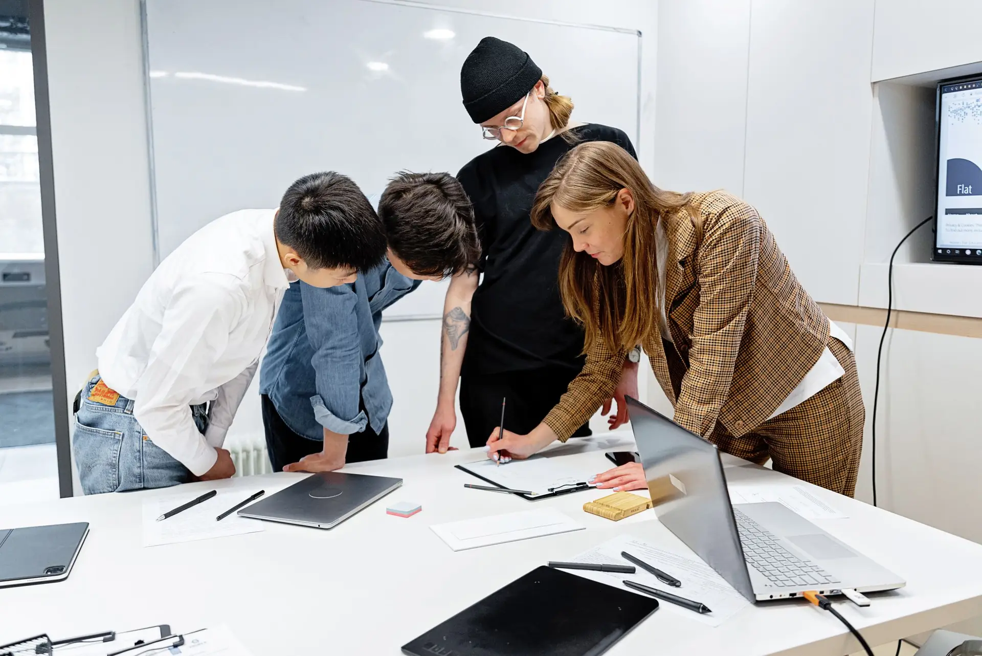 Ein Team arbeitet stehend an einem Tisch gemeinsam an Notizen und Entwürfen